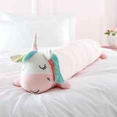 a stuffed unicorn laying on top of a white bed