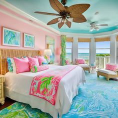 a bedroom decorated in pink, blue and green with a ceiling fan above the bed