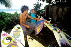 two people holding surfboards next to each other