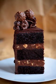 a piece of chocolate cake on a white plate with walnuts in the top layer