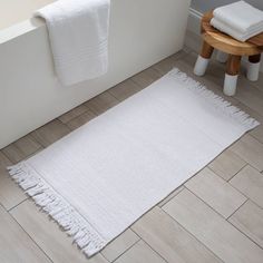 a white rug on the floor next to a bath tub