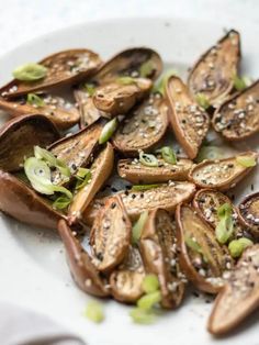 a white plate topped with sliced mushrooms covered in sesame seeds