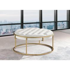 a white and gold coffee table sitting in front of large windows with cityscape behind it