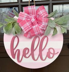 a pink and white door hanger with the word hello painted on it