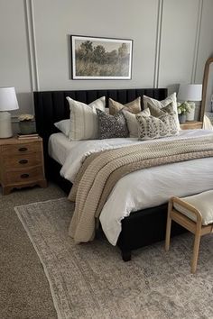 a bedroom with a large bed and mirror on the wall, along with two nightstands