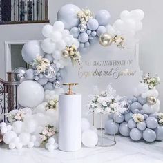 balloons and decorations are arranged on the floor for an anniversary celebration with white and silver colors