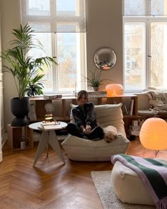 a person sitting on a couch in a living room with two lamps and a dog