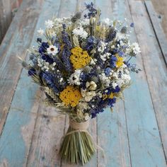 a bouquet of wildflowers and daisies on a wooden table with blue paint