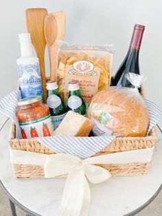 a basket filled with bread, cheese and other items on top of a white table