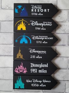 three wooden signs with disney world and disneyland parks on them hanging from a brick wall