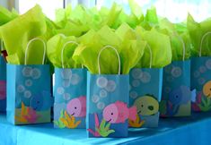 some little bags that are on top of a table with green tissue flowers in them