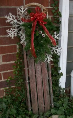 a wooden sled with snowflakes on it and a red bow hanging from the top