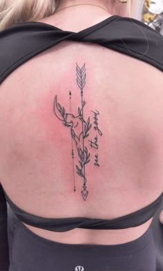 a woman's back with an arrow tattoo on it