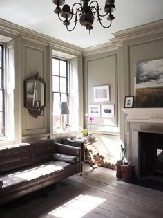 a living room filled with furniture and a fire place under a chandelier on top of a wooden floor