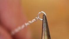 a close up of a person holding a piece of metal with a chain attached to it