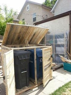 an outdoor storage shed with the door open and trash cans in it's back yard