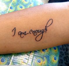 a woman's arm with the word i am enough written on it, in cursive font