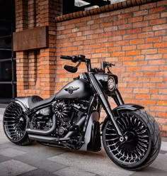 a black motorcycle parked next to a brick wall