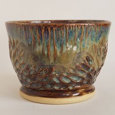 a ceramic bowl with brown and green designs on the outside, sitting on a white surface