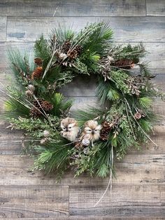 a christmas wreath with pine cones and other evergreen leaves on a wooden surface, ready to be used as an ornament