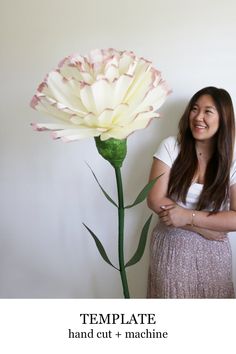 a woman standing next to a large flower