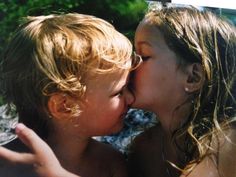 two children are kissing each other in the water