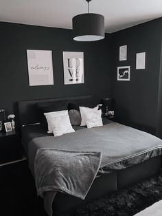 a black and white photo of a bed in a room with pictures on the wall