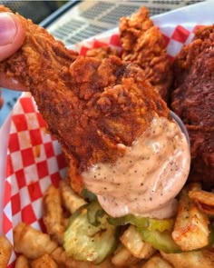 a person dipping sauce on fried food in a basket