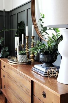 a wooden dresser topped with plants and candles