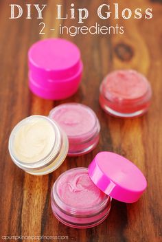 four jars of pink and white lip polish sitting on a wooden table next to each other