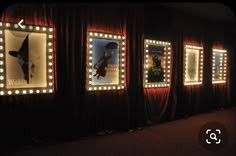 a row of lighted mirrors on the side of a wall in front of red curtains