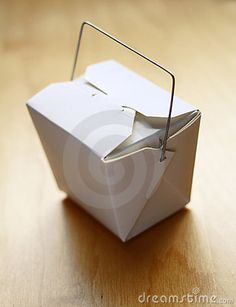 an origami box with a handle on a wooden table, close - up