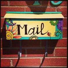 a mailbox with the word mail painted on it's front and side, attached to a brick wall