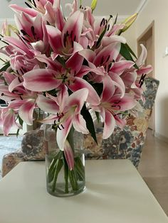 a vase filled with pink flowers sitting on top of a table next to a couch