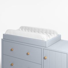 a baby crib with two drawers and a white blanket on it's side