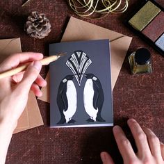 a person is drawing two penguins on a card