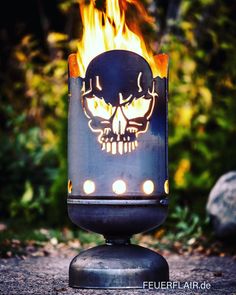 a lit up fire pit with a skull on it's face and flames in the background