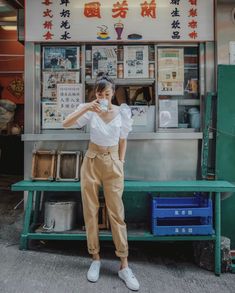 a woman standing in front of a food stand with her hands on her hips and looking at the camera