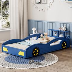 a child's bedroom with a blue car bed and toy cars on the floor