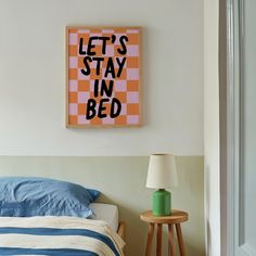 a bed sitting under a painting on the wall next to a nightstand with a lamp