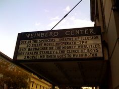 a theater sign hanging from the side of a building