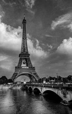 black and white photograph of the eiffel tower with clouds in the sky above