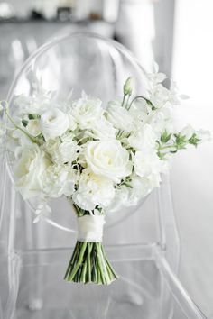 a bouquet of white flowers sitting on top of a clear chair