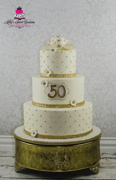 a white and gold wedding cake with the number 50 on it's tiers