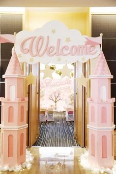 a pink and white welcome sign at the entrance to a room with wooden flooring