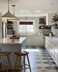 a kitchen with two stools next to an island