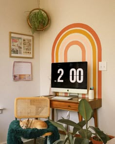 a computer monitor sitting on top of a desk next to a potted green plant