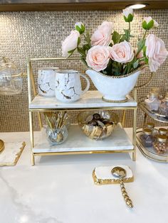 three tiered trays with roses and other items on top of them, along with a gold key