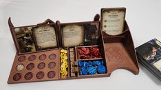 an open wooden box with cards, dices and other items in it on a white surface