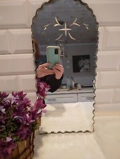 a woman taking a selfie in front of a mirror with flowers on the counter